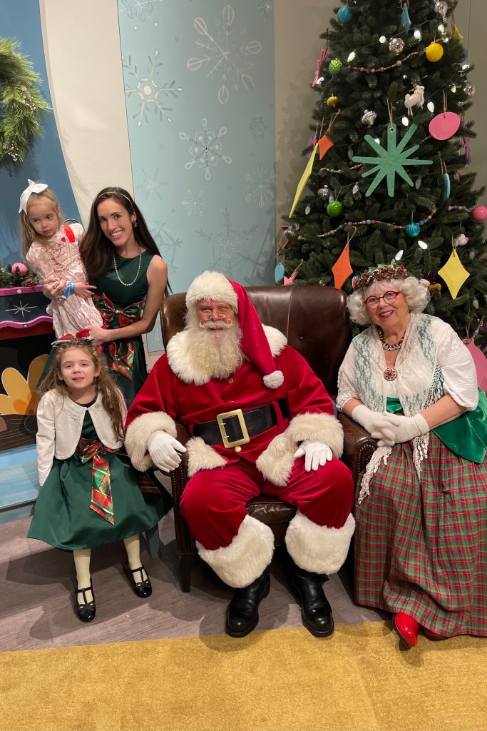 mother and two daughters in holiday dresses with santa and mrs. claus at the indiana state museum