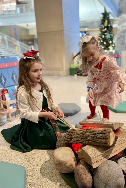two little girls roasting pretend marshmallows at indiana state museum's celebration crossing