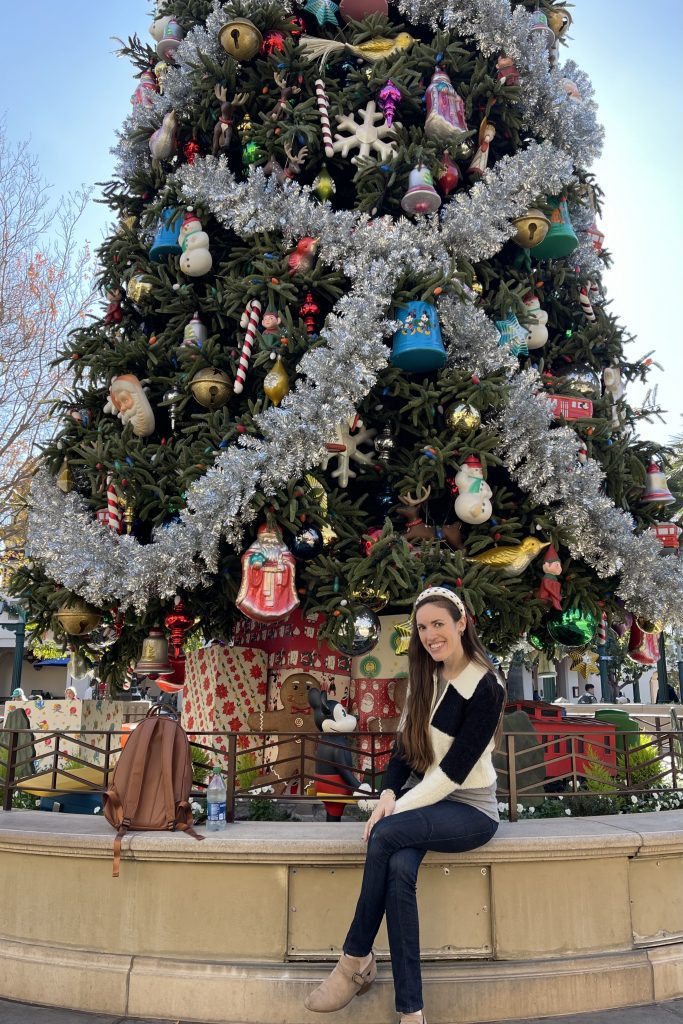 woman sitting by 50 foot christmas tree at disney california adventure park